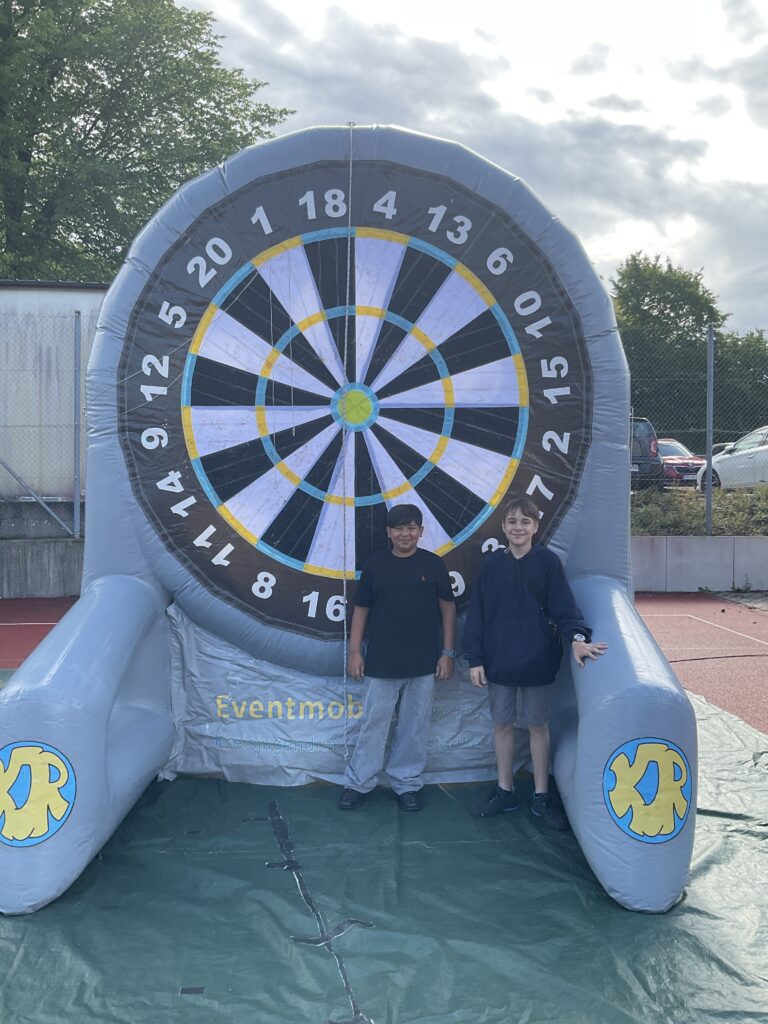 Zwei Schüler stehen vor dem riesigen Fußball-Dart auf dem Sportplatz.