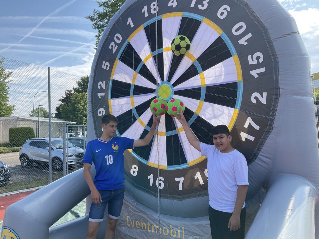 Zwei Jungen stehen vor der Fußball-Dartscheibe und zeigen, welche Bälle ihre Schüsse waren.