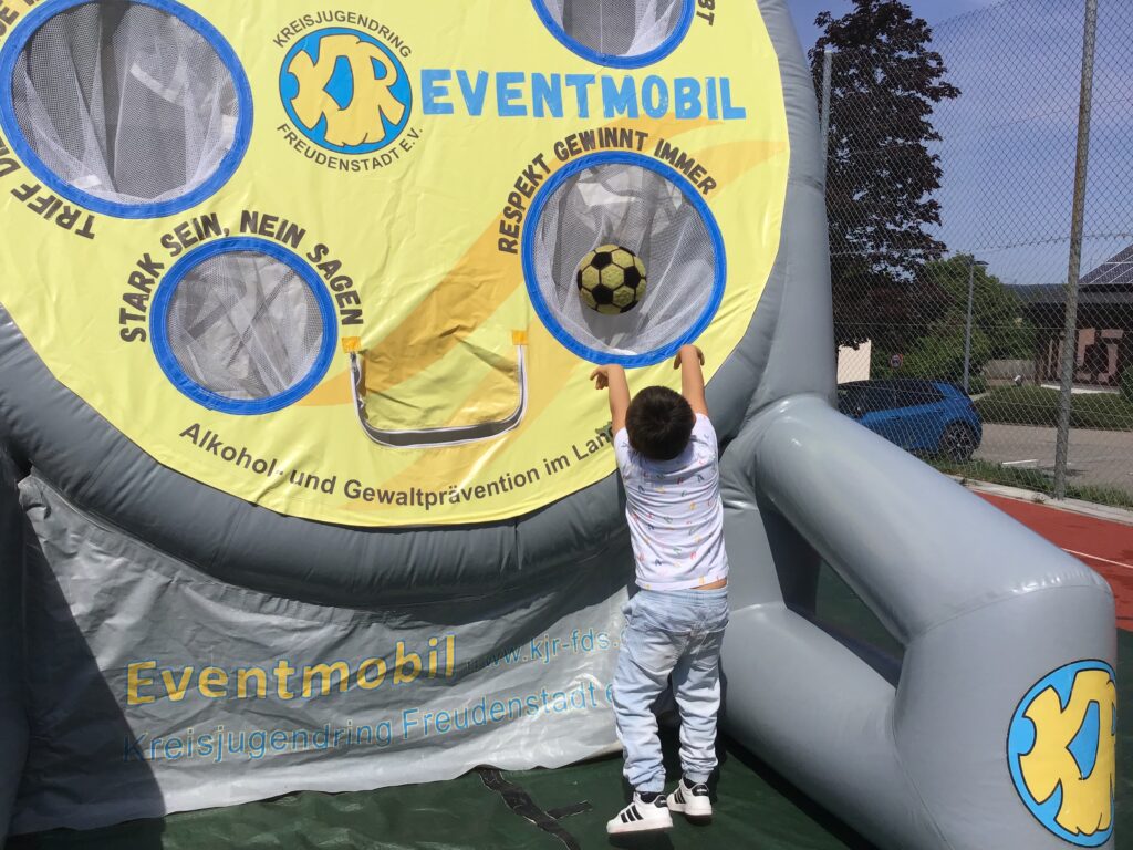 Ein Junge wirft den Ball in eines der Löcher des Fußball-Dart.